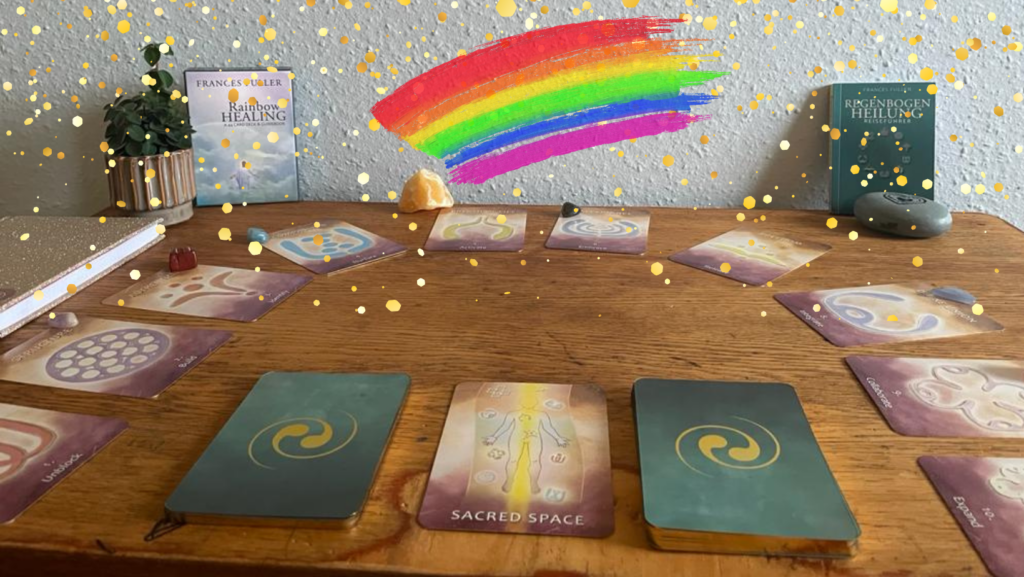 Rainbow Healing Karten liegen auf einem Holztish mit passenden Edelsteinen